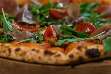 Pepperoni pizza with arugula and prosciutto. Meat pizza with cheese, cherry tomatoes and fresh arugula on a white background