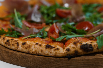 Pepperoni pizza with arugula and prosciutto. Meat pizza with cheese, cherry tomatoes and fresh arugula on a white background