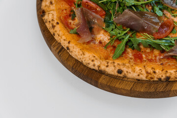 Pepperoni pizza with arugula and prosciutto. Meat pizza with cheese, cherry tomatoes and fresh arugula on a white background