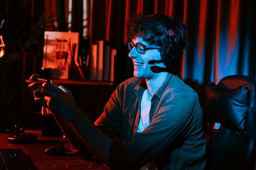 Smiling young gaming streamer team playing with Esport online on smartphone fighting wearing headphones at neon light room. Practising strategy plan to win competitors for next harder level. Gusher.