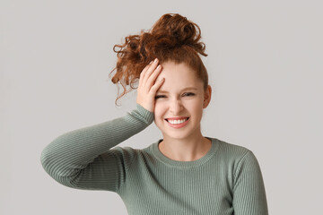 Portrait of ashamed young woman covering face on brown background
