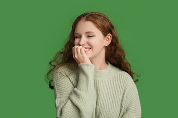 Portrait of shy young woman on green background