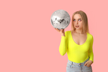 Beautiful young woman with disco ball on pink background