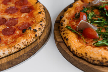 Pizza set with meat and cheese. Pepperoni pizza with arugula and prosciutto. Meat pizza with cheese, cherry tomatoes and hot peppers on a white background