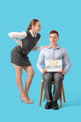 Business man holding paper with text STOP HARASSMENT and his female colleague on blue background