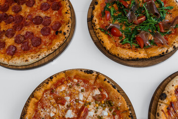 Pizza set with meat and cheese. Pepperoni pizza with arugula and prosciutto. Meat pizza with cheese, cherry tomatoes and hot peppers on a white background