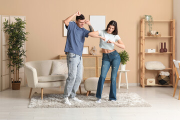 Happy young couple dancing in living room