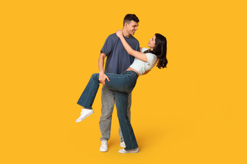 Beautiful young couple dancing on yellow background