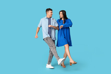 Obraz premium Happy young couple dancing on blue background