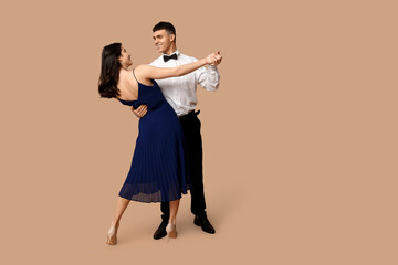 Beautiful young couple dancing on brown background