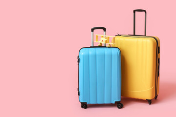Suitcases and toy airplane on pink background. Travel concept