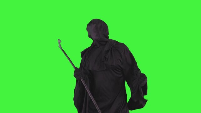 Grim reaper in Halloween costume holding a scythe dancing joyfully on a green screen