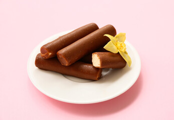Plate with tasty chocolate glazed curd snacks with vanilla flavor on pink background