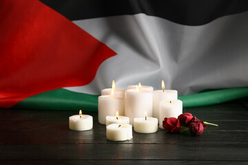 Flag of Palestine, rose flowers and burning candles on black wooden background