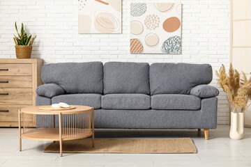 Interior of beautiful living room with cozy sofa, pictures, chest of drawers and coffee table