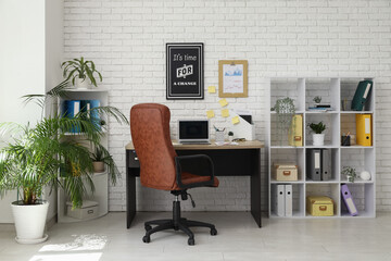 Interior of office with workplace, brown armchair, modern laptop and shelving unit