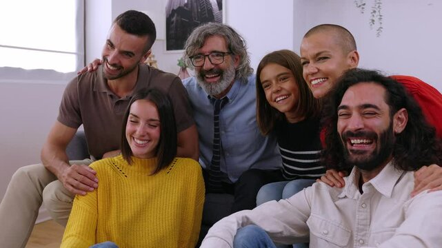 Side view of multigenerational happy family sitting together on sofa at home. Photo group of grandfather, mother, father, aunt, ancle and granddaughter relaxing in the living room.
