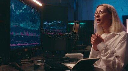 Happy woman girl businesswoman crypto trader influencer blogger cyber streamer business tutor coach talk microphone dark night studio record audio podcast online stream stock chart on computer screen - Powered by Adobe