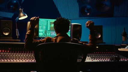 African american music producer vibing on his new track in professional studio, mixing and...