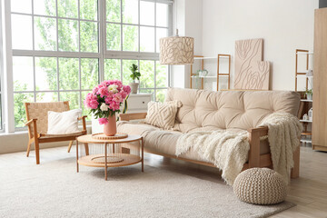 Fototapeta premium Armchair, sofa and coffee table with peonies in interior of living room