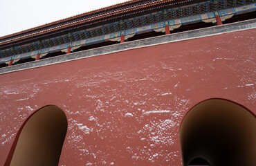 A red wall with snow patterns and large arched openings, topped with intricate decorative eaves....