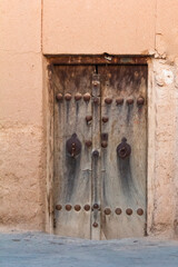 Antique wooden garden door with a plank, knocker and other ornaments in details	