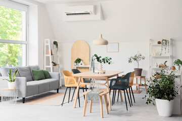Interior of light room with dining table, sofa and plants