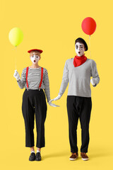 Couple of pantomimists with balloons on yellow background