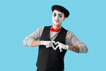 Male pantomimist making heart with his hands on blue background