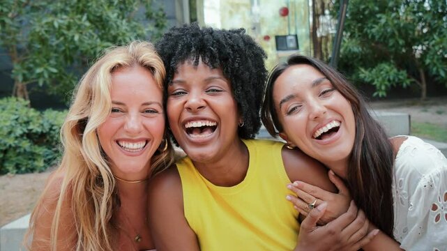 Group of young women smiling and looking at camera. Three multiracial teenage girls having fun together. Joyiful females laughing and gazing front. Feminine ladies bonding enjoying at their vacations