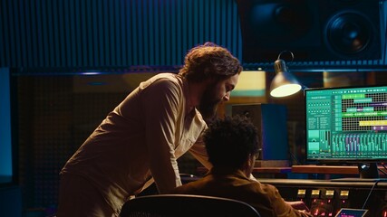 Diverse team of musician and audio technician creating a hit song, working in professional music...