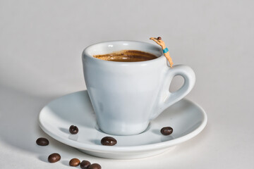A bather jumps into a cup with coffee, coffee beans on the plate