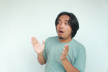 Shocked and surprised face of Asian man in green t-shirt and long hair.