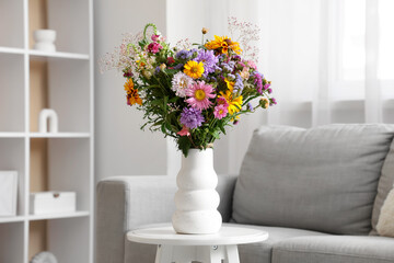 Vase with wild flowers on coffee table in interior of living room. Closeup