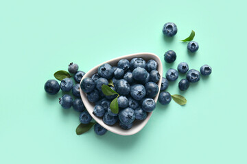 Bowl with ripe blueberry on turquoise background