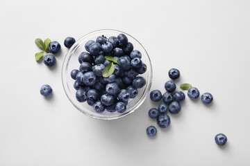 Glass bowl of fresh ripe blueberry on white background