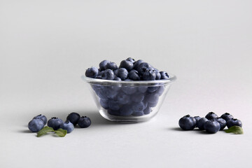 Glass bowl of fresh ripe blueberry on white background