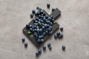Black cutting board with fresh ripe blueberry on grunge background