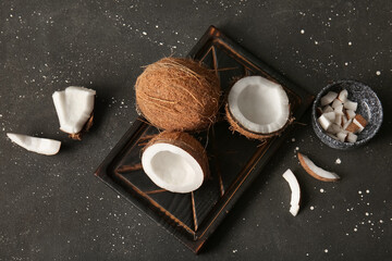 Wooden board with fresh coconuts on black background