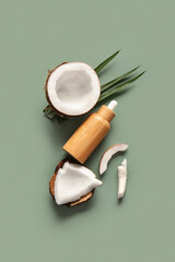 Bottle of coconut cosmetic oil and palm leaves on green background