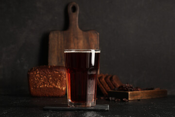 Glass of fresh kvass and bread on black background