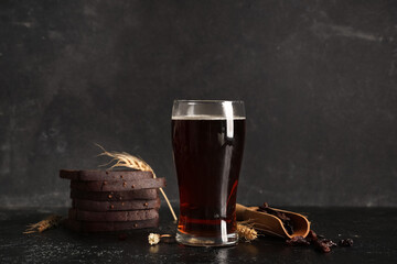 Glass of fresh kvass with slices of bread and wheat on black background