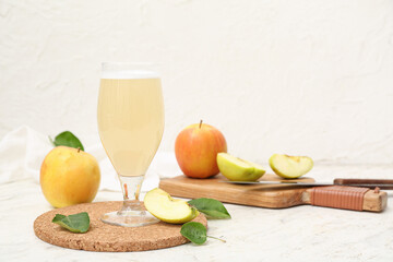 Glass of fresh apple kvass and wooden board with fruits on white background