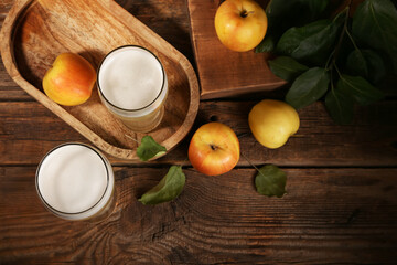 Glasses of fresh apple kvass and fruits on wooden background