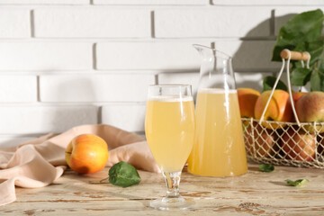 Glass and jug of fresh apple kvass on white wooden table