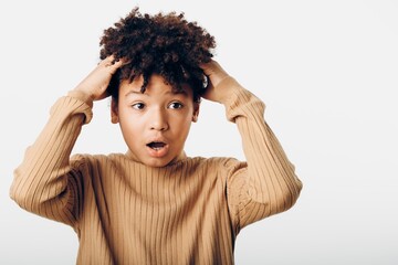 Young african american girl with hands on her head and a surprised expression, gazing upward in awe