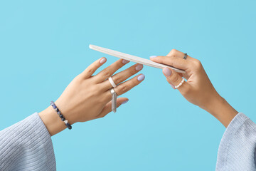 Female hands with stylish manicure and nail file against color background, closeup