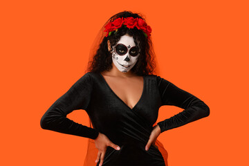 Young African-American woman dressed for Halloween on orange background