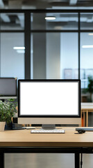 Modern office workspace with a blank computer screen, potted plant, and neat desk setup in open-plan office environment.