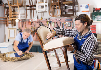 Craftsman in process of creation wooden furniture in workshop